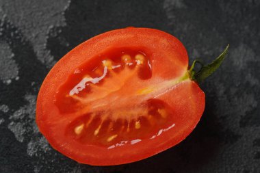 Kesilmiş taze domates parçası koyu arkaplanda. Damlacıklı domates. Kapat.