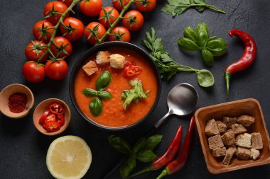 Endülüs usulü gazpacho. Bardakta soğuk kırmızı domates çorbası, salatalık, soğan, fesleğen, acı biber ve kızarmış ekmek..