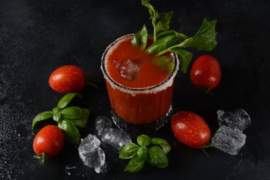 Bir bardak taze domates suyu ve domatesler koyu arka planda su damlalarıyla