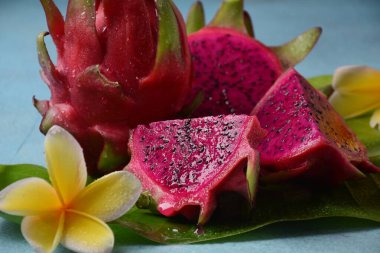 Ejderha meyvesi (Pitaya, Pitahaya) Bir tam, iki dilimlenmiş piespitahaya meyvesi, ve frangipani çiçekleri.