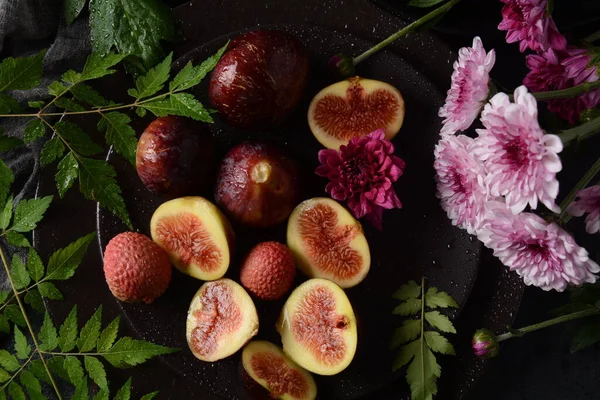Raw fresh fig fruit slices with organic lychee fruit. Fresh lychee and peeled showing the red skin and white flesh on dark background.