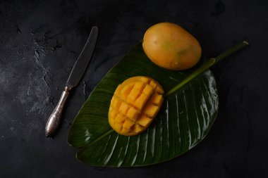 Dilimlenmiş mango parçalı taze mango meyvesi tabakta ya da yapraklarda arka plan olarak. 