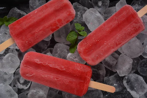 Strawberry popsicle on ice background