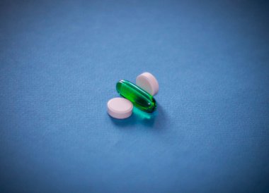 Oval beyaz hap mavi zemin üzerine yeşil tablet ile. Tıp ve sağlıklı