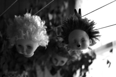 Plastik bebek kafaları bir ip üzerinde yeşil arka plan asılı. Kırmızı, kestane ve beyaz saçlı bebek.