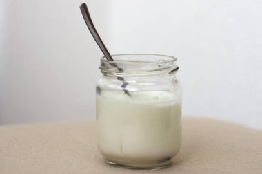 Kahvaltı için cam kavanozda beyaz yoğurt.