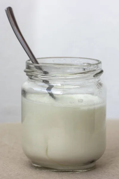 Yogur blanco en frasco de vidrio en la mesa para el desayuno — Foto de Stock