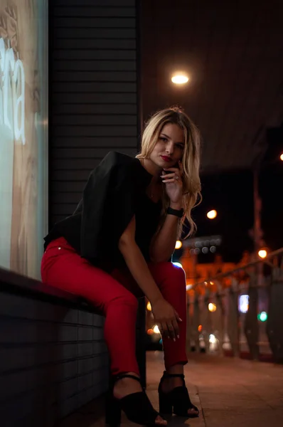 Сексуальная молодая красавица, позирующая над ночным городом, освещенная уличным фоном. Отпуск. Молодая стильная блондинка с длинными волосами — стоковое фото