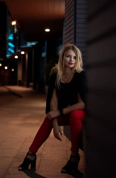 Sexy young beauty woman posing over night city illuminated street background. Vacation holidays. Young stylish woman blonde with long hair