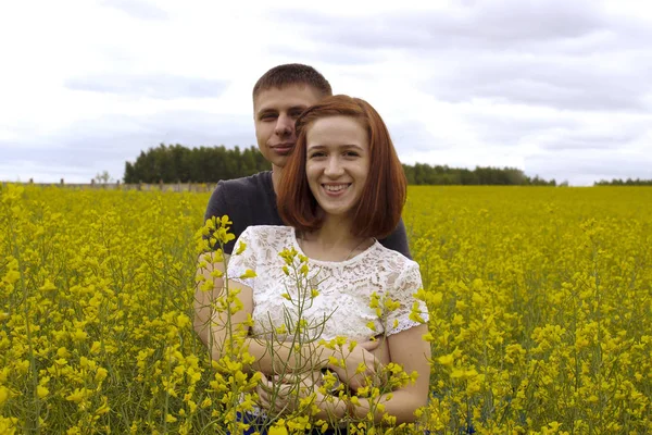 Belo casal em um campo de colza amarelo — Fotografia de Stock