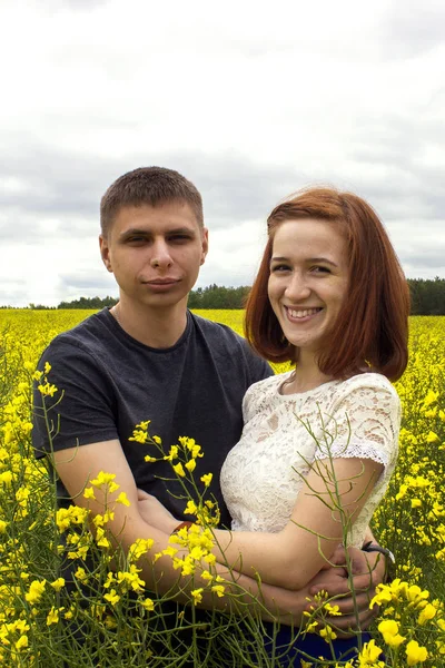 Belo casal em um campo de colza amarelo — Fotografia de Stock