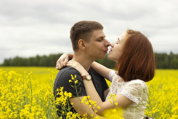 Belo casal beijos em um campo de colza amarelo — Fotografia de Stock