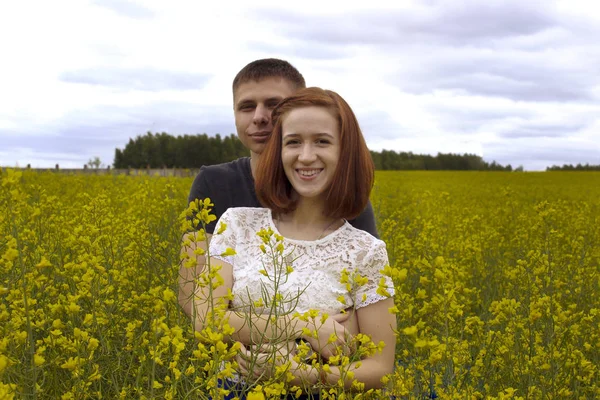 Belo casal segurando um ao outro em um campo de colza — Fotografia de Stock