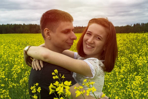 Beautiful couple holding each other in a rapeseed field — Stock Photo, Image