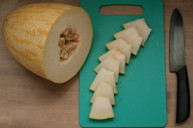 Tahta masa üzerinde kesme tahtası üzerinde dilimlenmiş taze kavun