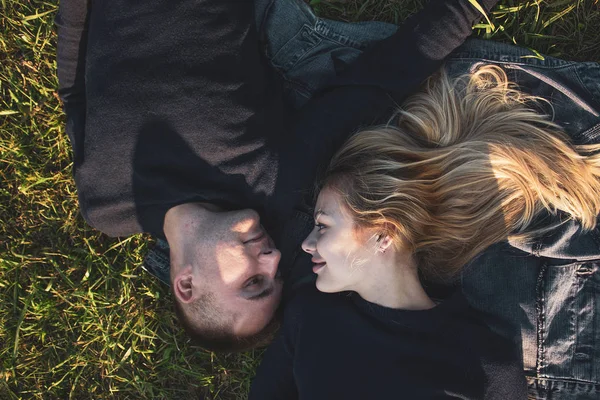 Vista superior de um jovem casal romântico deitado na grama em um jeans no parque . — Fotografia de Stock