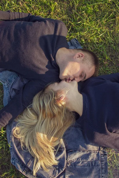 Vista superior de um jovem casal romântico deitado na grama em um jeans no parque . — Fotografia de Stock