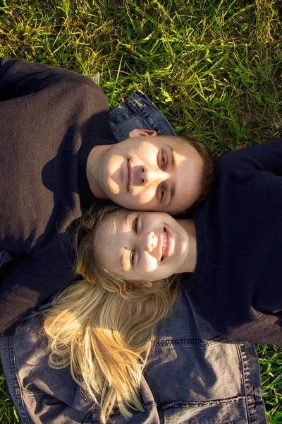 Vista superior de um jovem casal romântico deitado na grama em um jeans no parque . — Fotografia de Stock