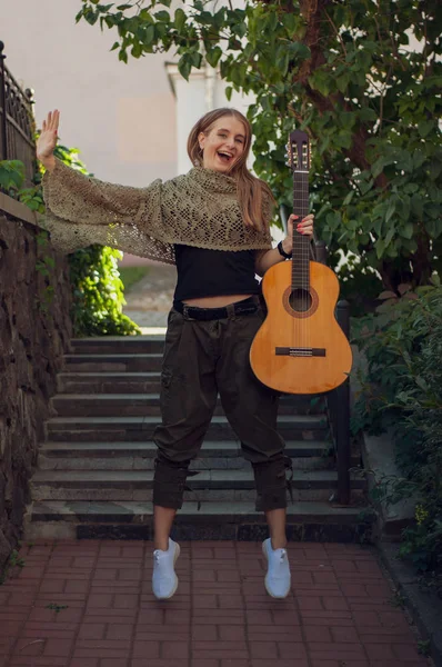 girl jumps up with a guitar in her hands