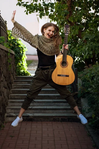 girl jumps up with a guitar in her hands