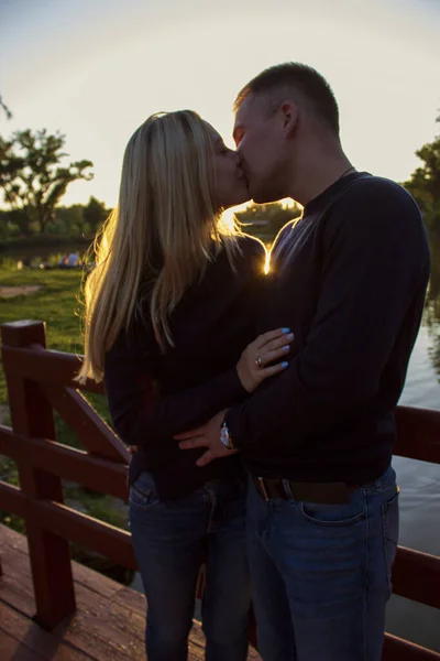 Щаслива молода пара цілується на пірсі на фоні заходу сонця — стокове фото