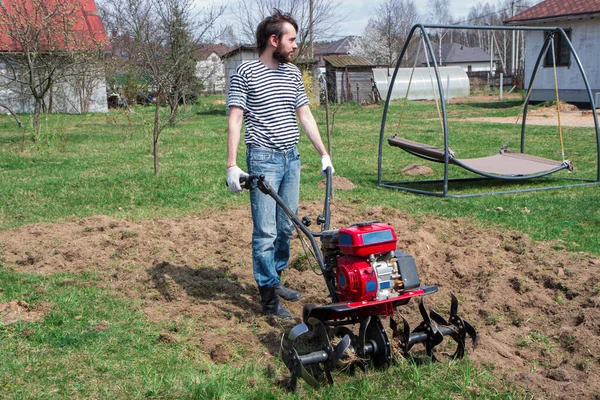 庭で庭師と仕事をしている男 春に畑を耕し耕すトラクターは — ストック写真