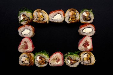 Meydanda suşi hazır. Siyah arkaplanda suşi olan çerçeve, üst görünüm.