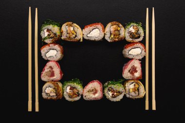 Üzerinde suşi ve yemek çubuğu olan çerçeve, üst manzara. Meydanda sushi hazır..