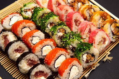 Büyük suşi seti farklı maki ile - hosomaki, futomaki ve uramaki üzerinde bambu eşleşmesi üzerine yakın plan