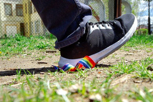 Trampling of LGBT flag in dirt by radical homophobe. Rainbow LGBT tape is stamped with feet.