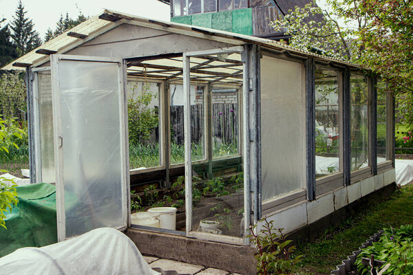 Old wooden homemade greenhouse from the glass windows in the garden