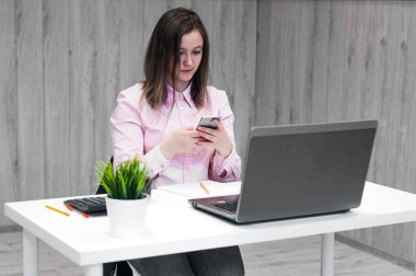 Businesswoman working with a smart phone sitting in a desktop at office