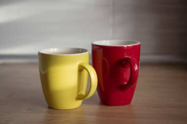 İki fincan sarı ve kırmızı kapuçino ile ahşap arka planda latte sanat. Güzel köpük, yeşillik seramik kaplar, tarz tonu, metin için yer.