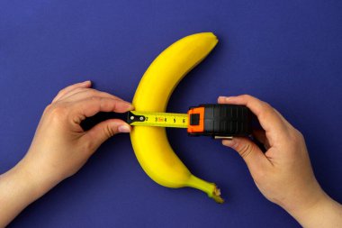 A measuring tape near a banana. The concept of penis enlargement, healthy eating, dieting and weight loss. male genital concept. mature content
