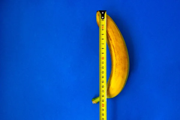 A measuring tape near a banana. The concept of penis enlargement, healthy eating, dieting and weight loss. male genital concept. mature content
