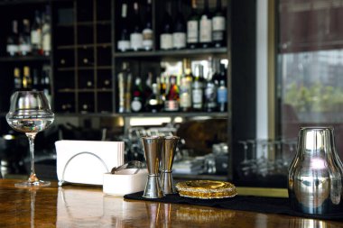 Barmen aletleri eski tarz bar tezgahında. Arka planda alkol olan bulanık şişeler.