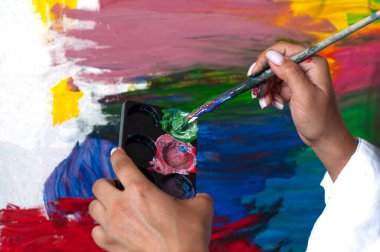 Ressam elinde boya fırçasıyla paleti yakından resmediyor. Palette guaj boyası karıştırmak, yaratıcı.