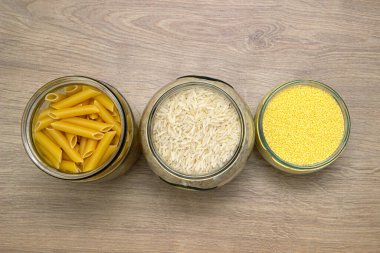 Tahta masadaki cam kavanozlarda pişmemiş mısır gevreği ve makarna çeşitleri. Sağlıklı yemek, temiz yemek, sıfır atık konsepti. Dengeli diyet yemekleri.