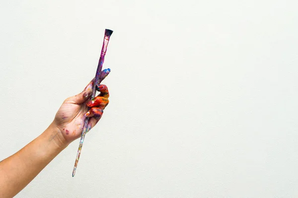 Close up of an artist or painter hands holding dirty paint brushes