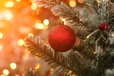 Süslü Noel ağacı arka planı. Kırmızı top ve el fenerleriyle aydınlatılmış çelenk. Bokeh 'le yeni yıl hediyesi makro fotoğraf. Kış tatili hafif dekorasyonu