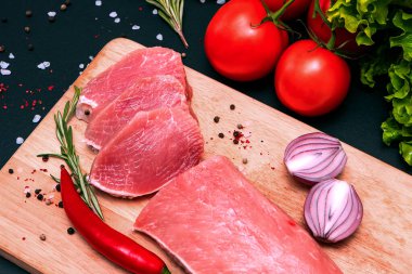 Çiğ, sulu biftekler siyah tebeşir tahtasında kızartılmaya hazır. Kiraz domatesli fileto, acı biber ve bitki..