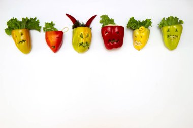 Beyaz arka planda farklı kesimlerde yüzleri olan çok renkli doldurulmuş biber. Cadılar Bayramı için kavram hazırlığı.