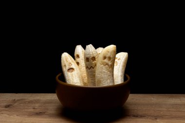 Ev yapımı, korkunç, yüzleri olan korkunç muz canavarları. Ahşap masada Cadılar Bayramı partisi için komik bir tatlı.