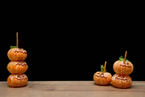 Halloween food. face on tangerine or mandarine orange fruits. Halloween minimal concept, a parody of pumpkins