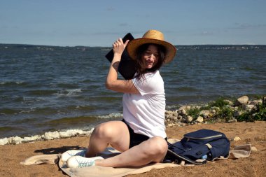 Kadın deniz kenarında çalışıyor ve bir dizüstü bilgisayar atmak istiyor. Serbest çalışan kadın sinirli, sinirli, üzgün. İşle ilgili sorun