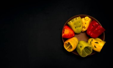 Farklı yüzleri kesilmiş çok renkli cadılar bayramı biberleri fotokopi alanı olan siyah bir arka planda. Cadılar Bayramı hazırlığı, yemek ve abur cubur hazırlığı