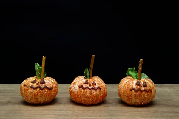 Halloween food. face on tangerine or mandarine orange fruits. Halloween minimal concept, a parody of pumpkins