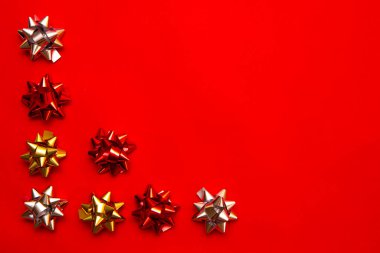 Noel süsü boş, kırmızı saten kurdele süsü. Fiyonklu Noel kompozisyonu. Kırmızı arka planda. Üst görünüm.