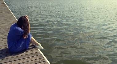 Rıhtımda nehir kenarında oturan üzgün kadın. İçe dönük, yorgunluk ve depresyon konsepti kopya alanı, metin için yer