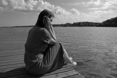 Rıhtımda nehir kenarında oturan üzgün kadın. İçe dönük, yorgunluk ve depresyon konsepti kopya alanı, metin için yer